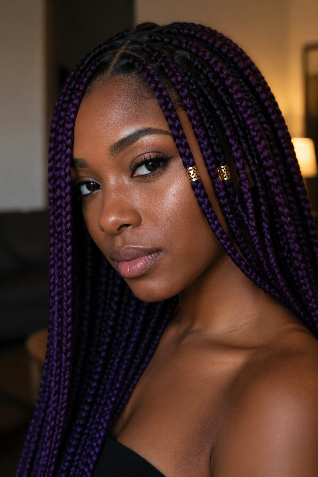 Close-up of a real person with amethyst purple box braids and gold cuffs near the face