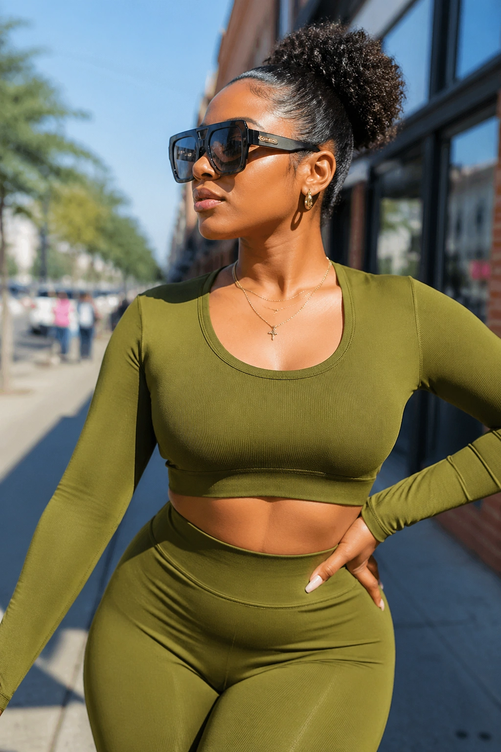 Woman in olive athletic set with sunglasses and slicked-back puff on city street
