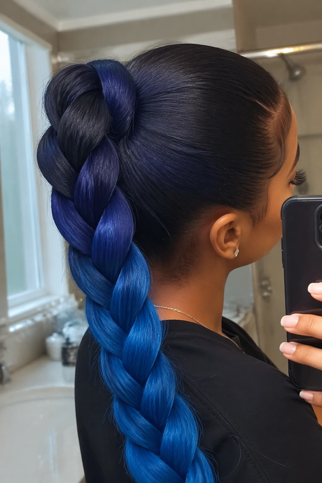 Close-up of Blue Ombré weave ponytail braid at root in soft bathroom light.
