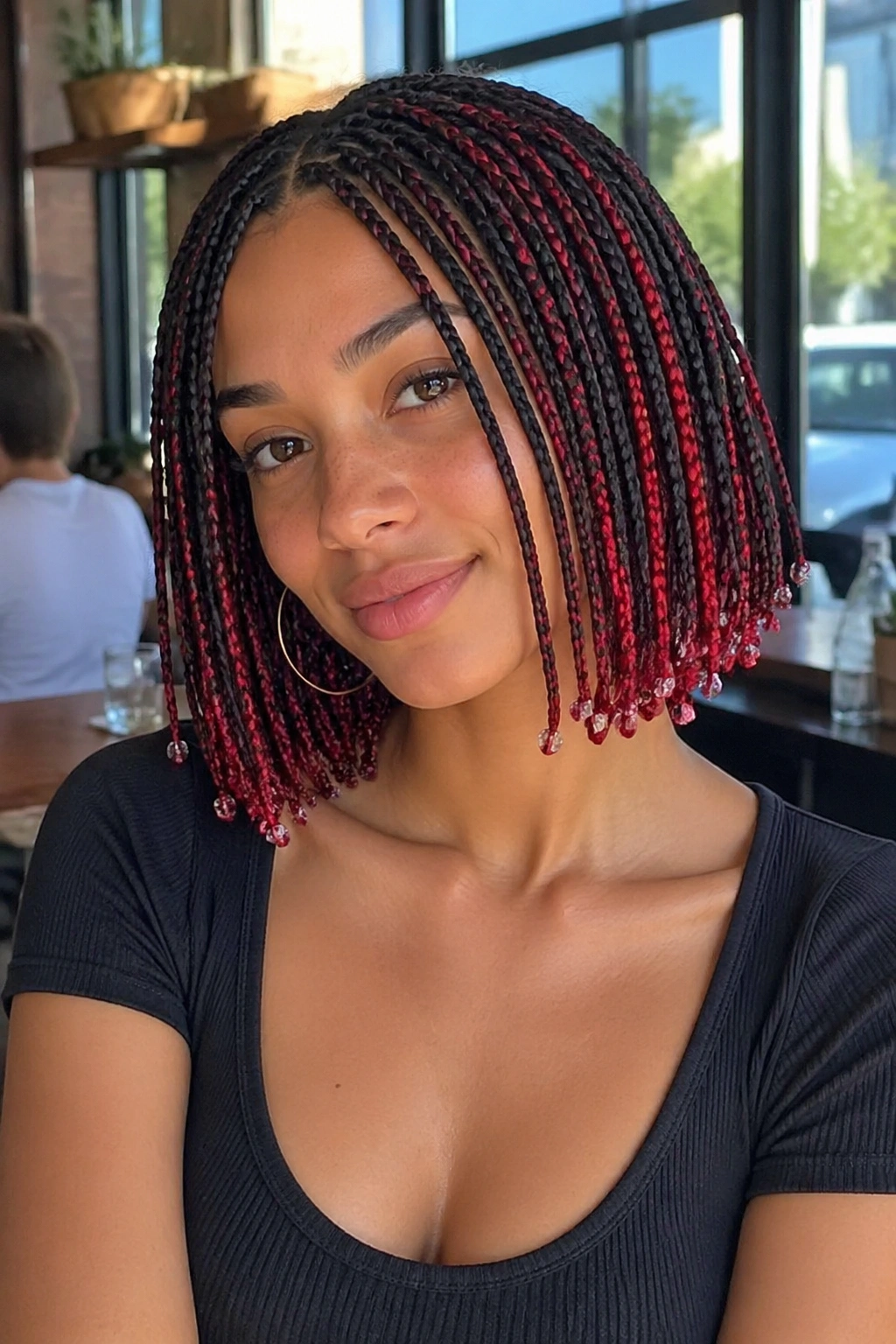 Close-up of a real person with bob-length scarlet peekaboo box braids and tiny beads