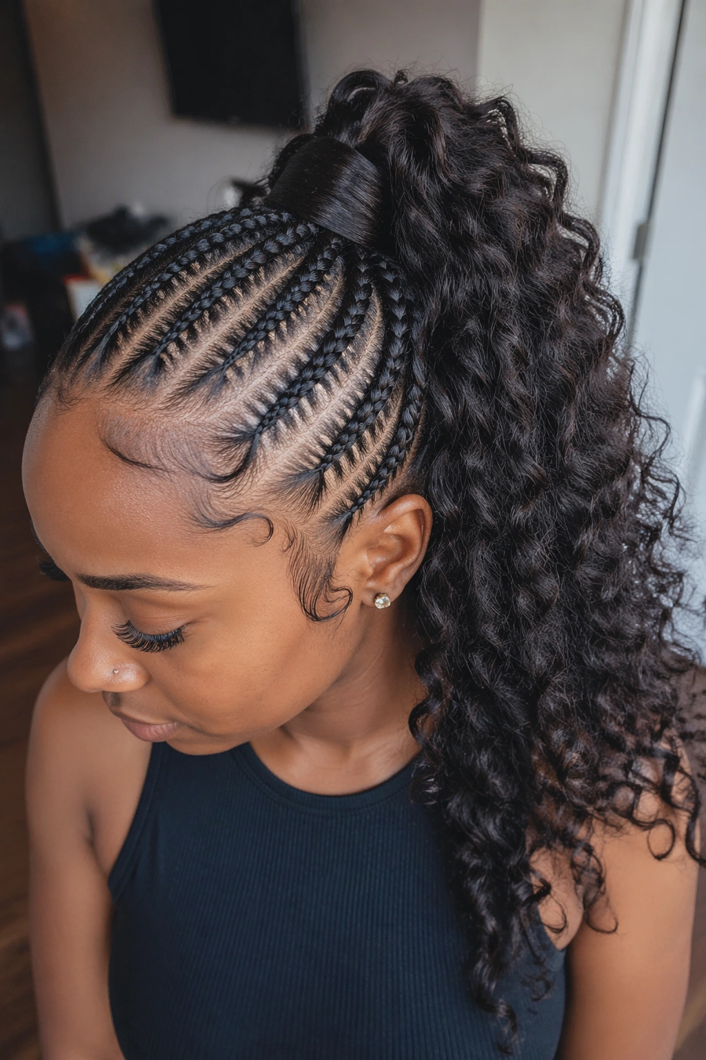 Real woman with cornrows gathered into a curly high ponytail.