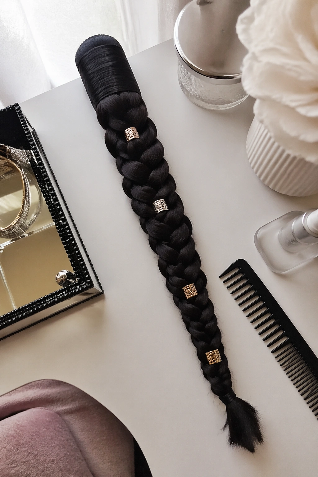 Overhead flat-lay of wrapped braid ponytail with cuffs and satin wrap.