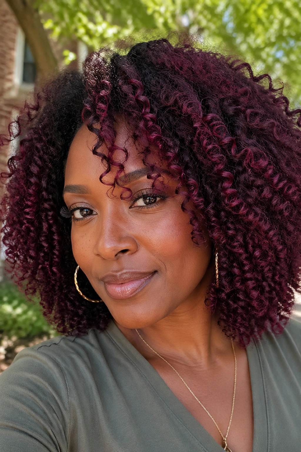 Close-up of dark curls with burgundy highlights in sunlight