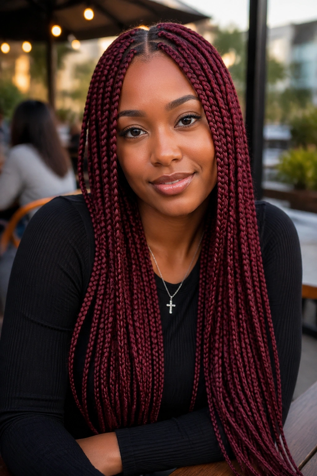 Portrait of a woman with burgundy knotless box braids in a middle part outdoors.