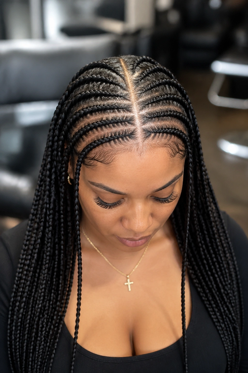 Portrait of a woman with a center-part cornrow design blending into box braids