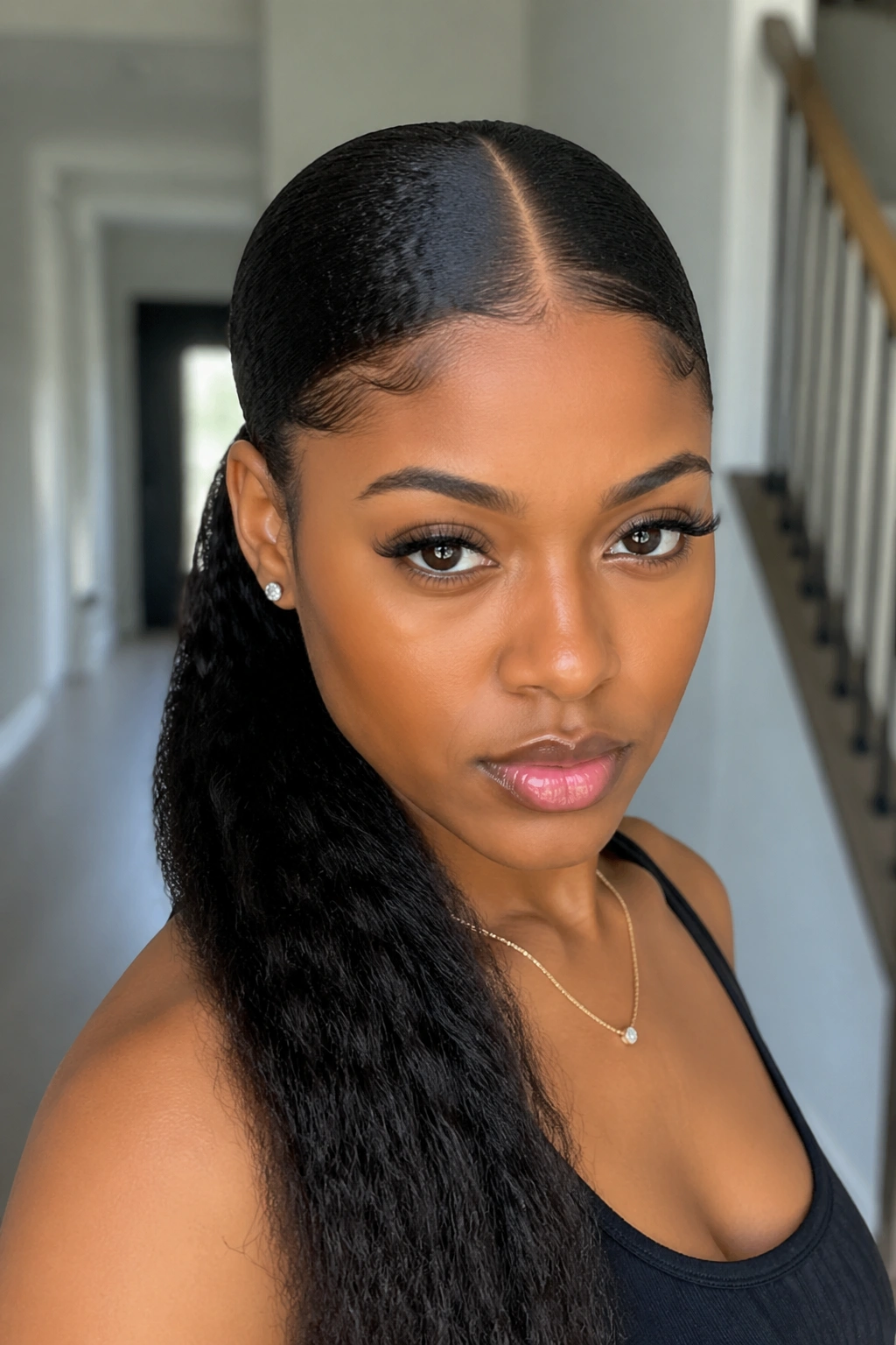 Close-up of a real woman with a crisp center-part and sleek ponytail.