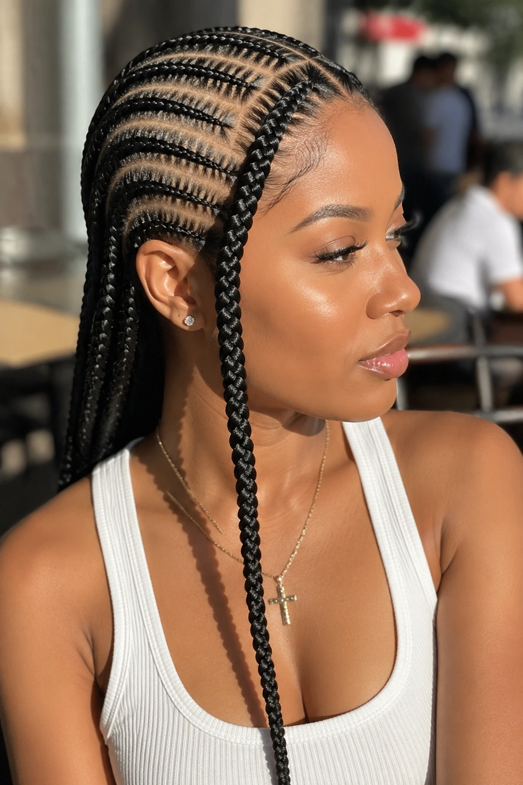 Portrait of a person with cascading side braid among straight-back cornrows.