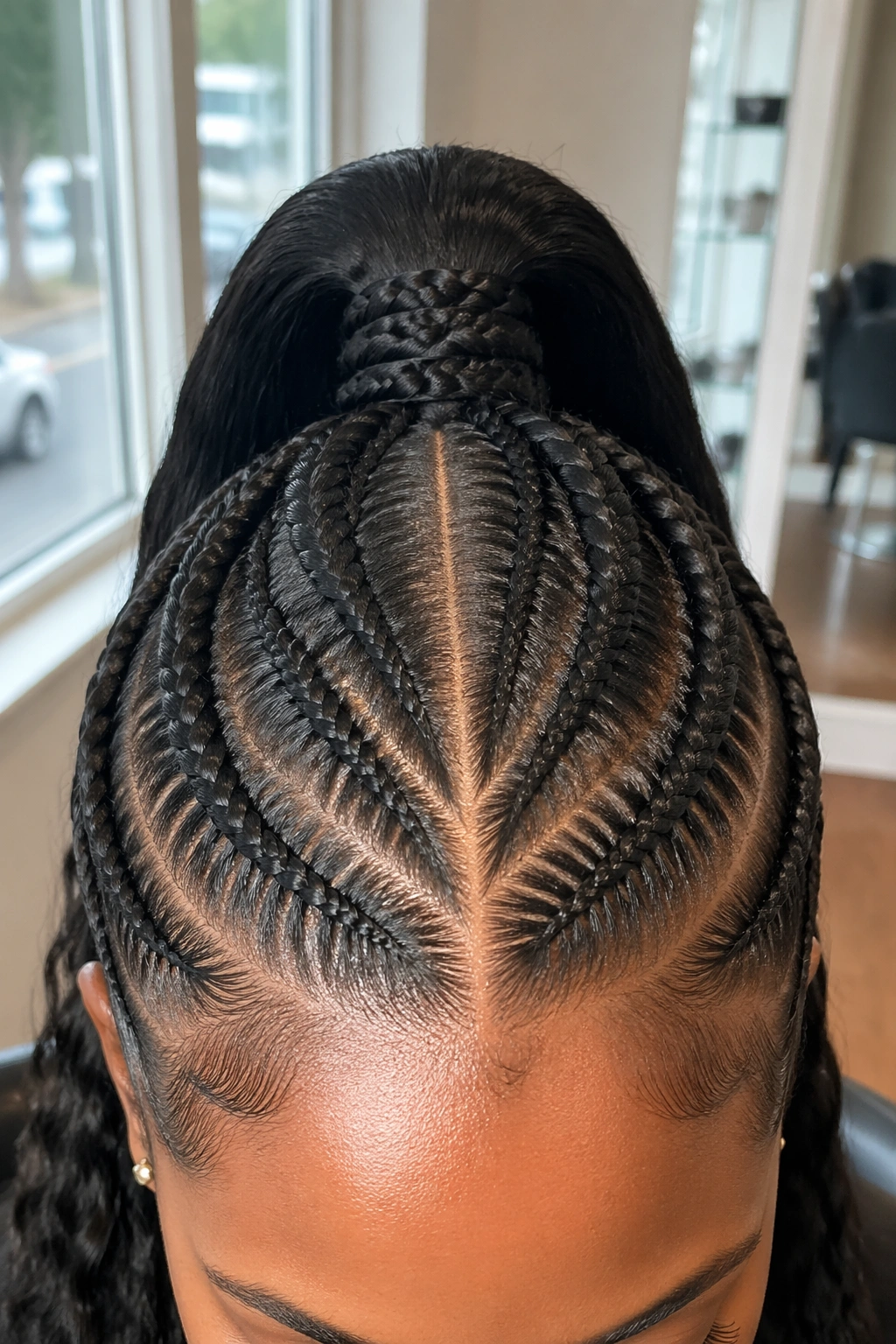 Close-up of center-part cornrows meeting at crown in salon light
