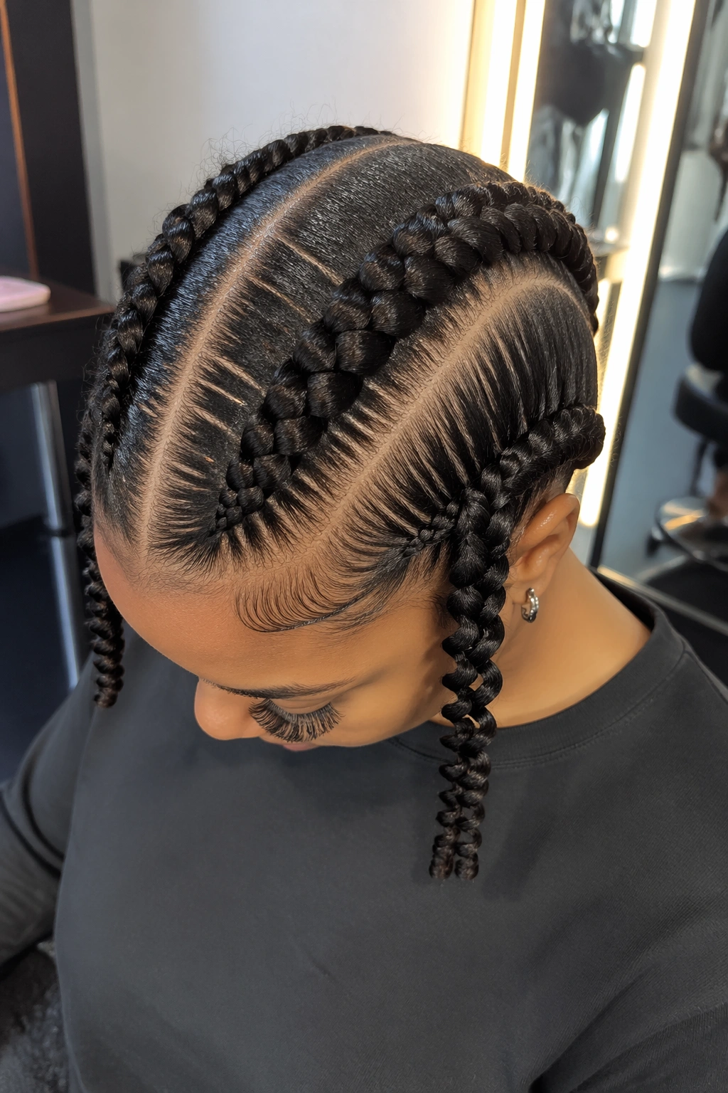 Macro close-up of two jumbo cornrows with spiral ends on curly hair.
