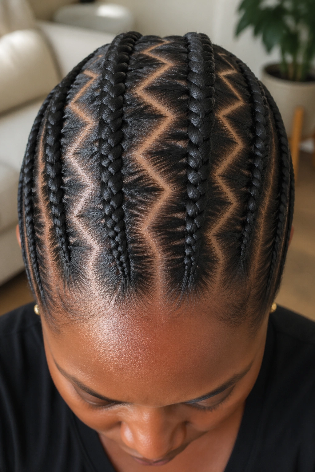 Top-down close-up of zigzag-parted straight-back cornrows on a real woman’s scalp