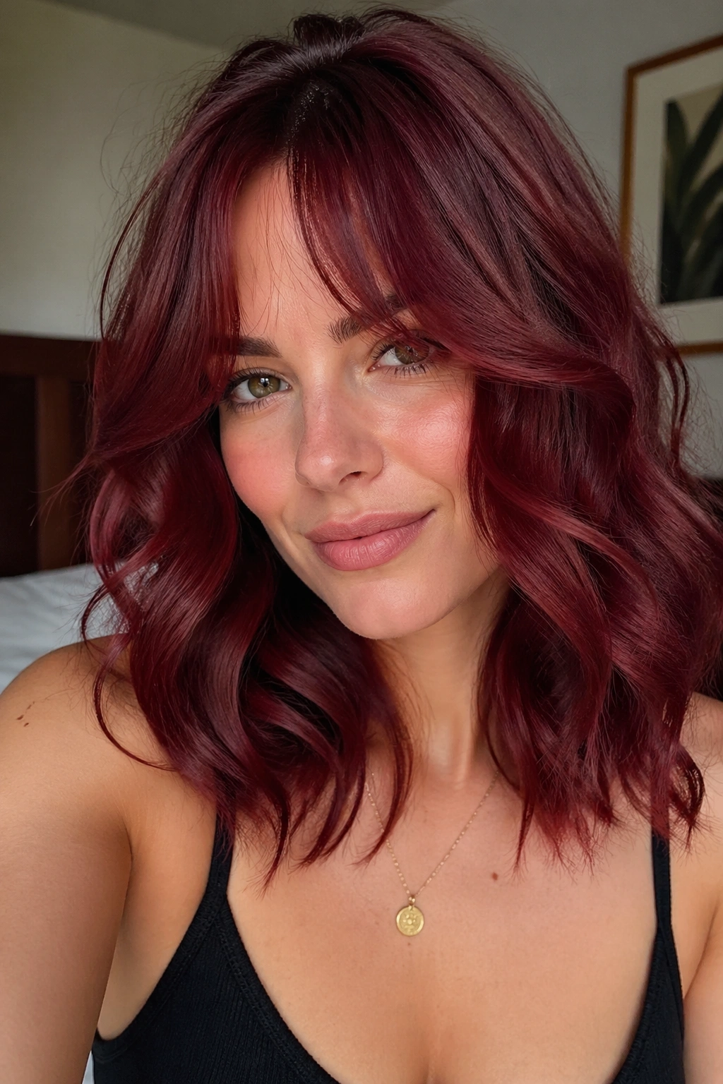 Close-up of a real woman with cranberry waves and curtain bangs in a cozy room