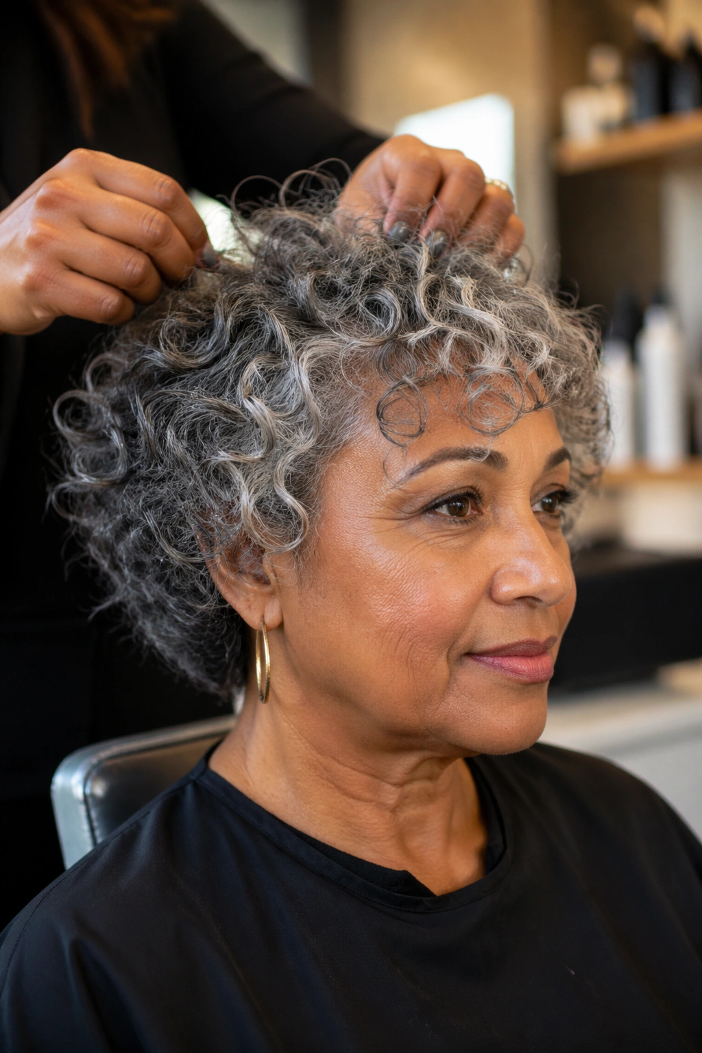 Close-up portrait of a real person in a salon chair showing grey curly bangs.