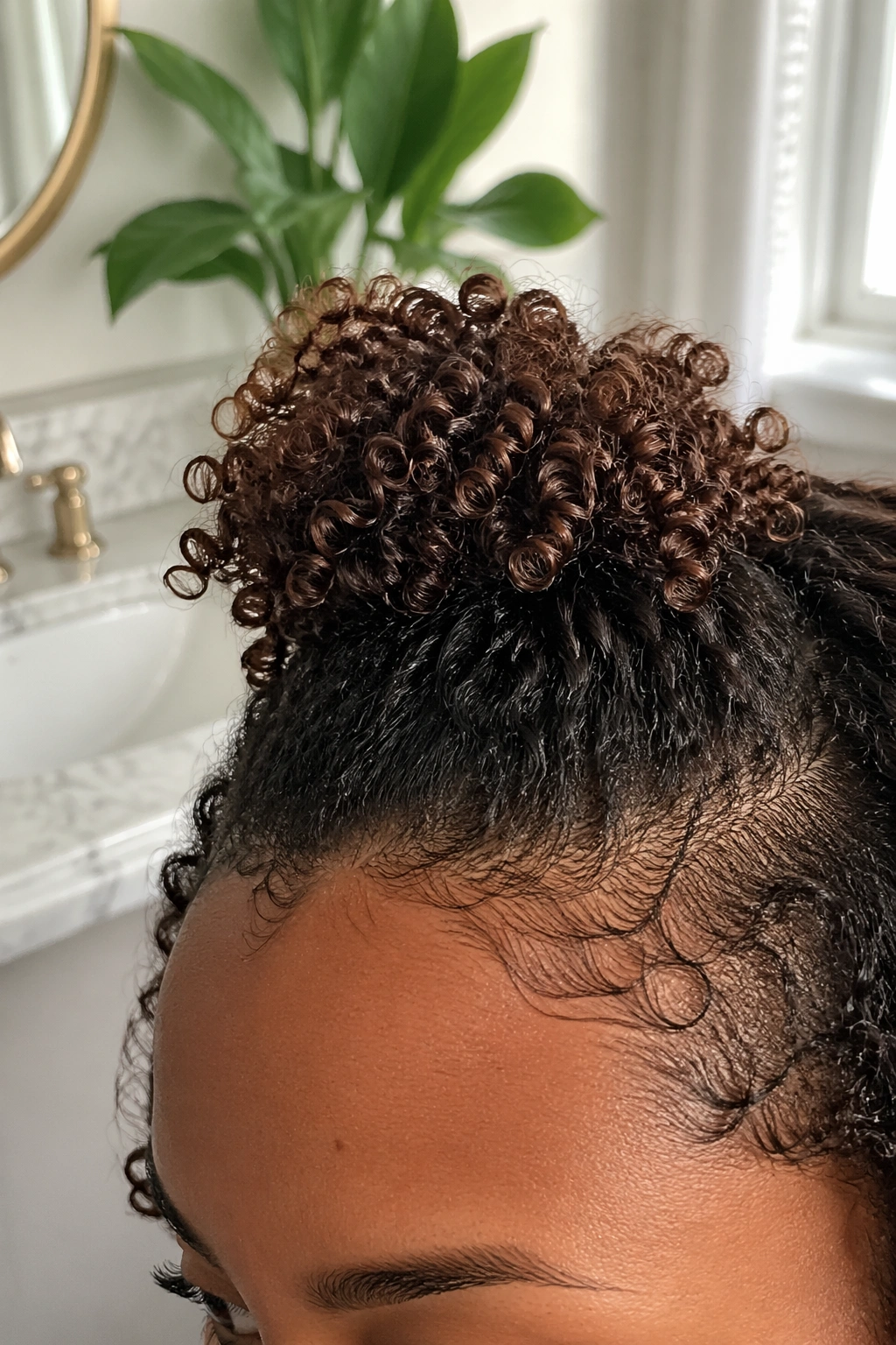 Close-up of mini curly puff at crown on short curls in a bathroom vanity.