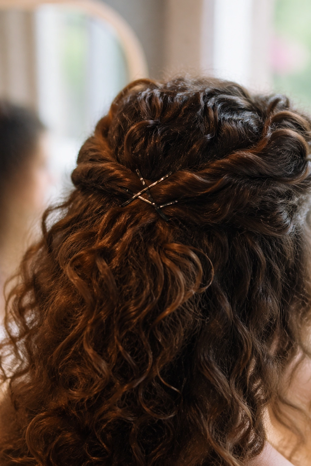 Close-up of two twisted crown sections in curly hair with pins, showcasing crown lift.
