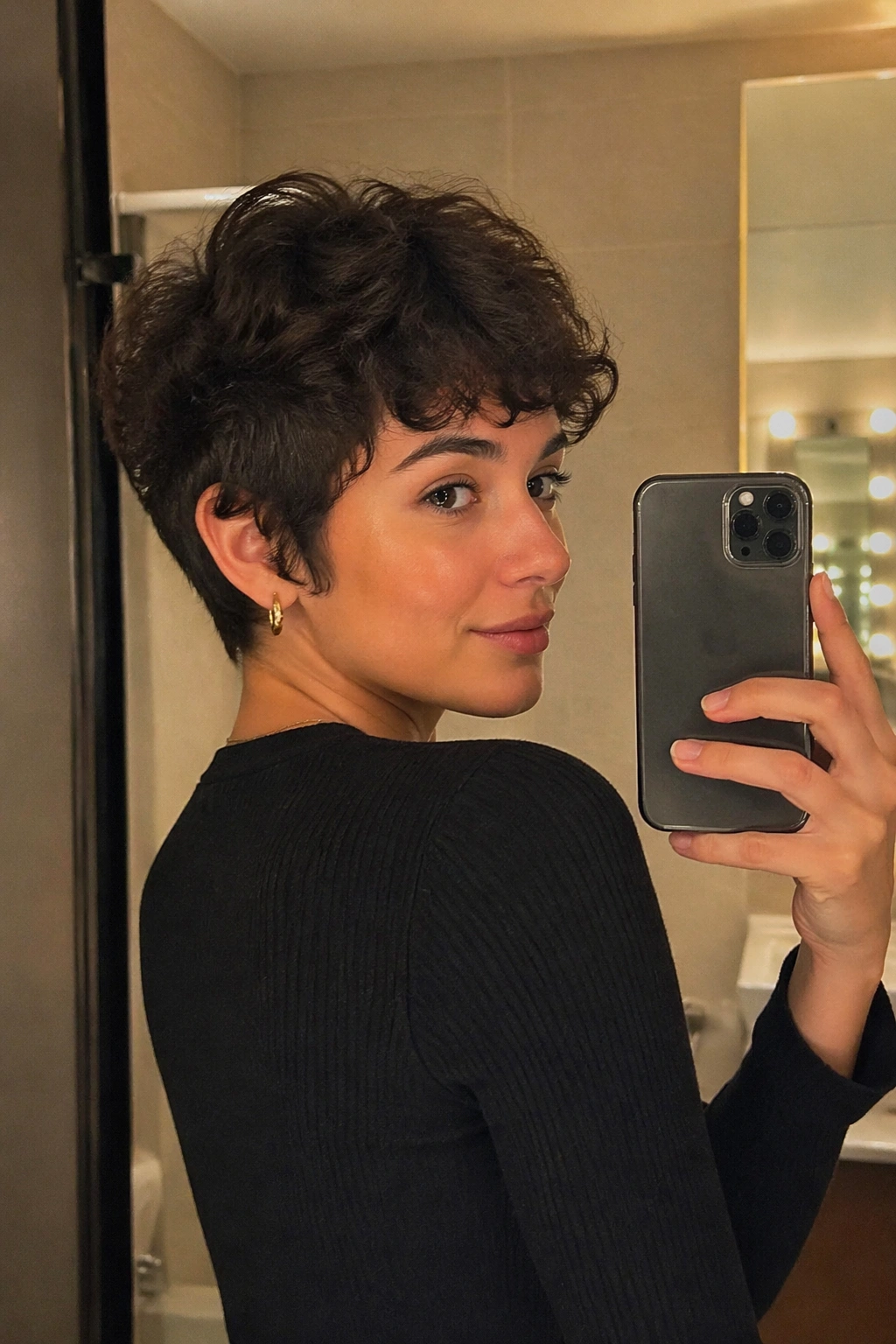 Three-quarter profile of a curly pixie with soft fringe in a mirror selfie