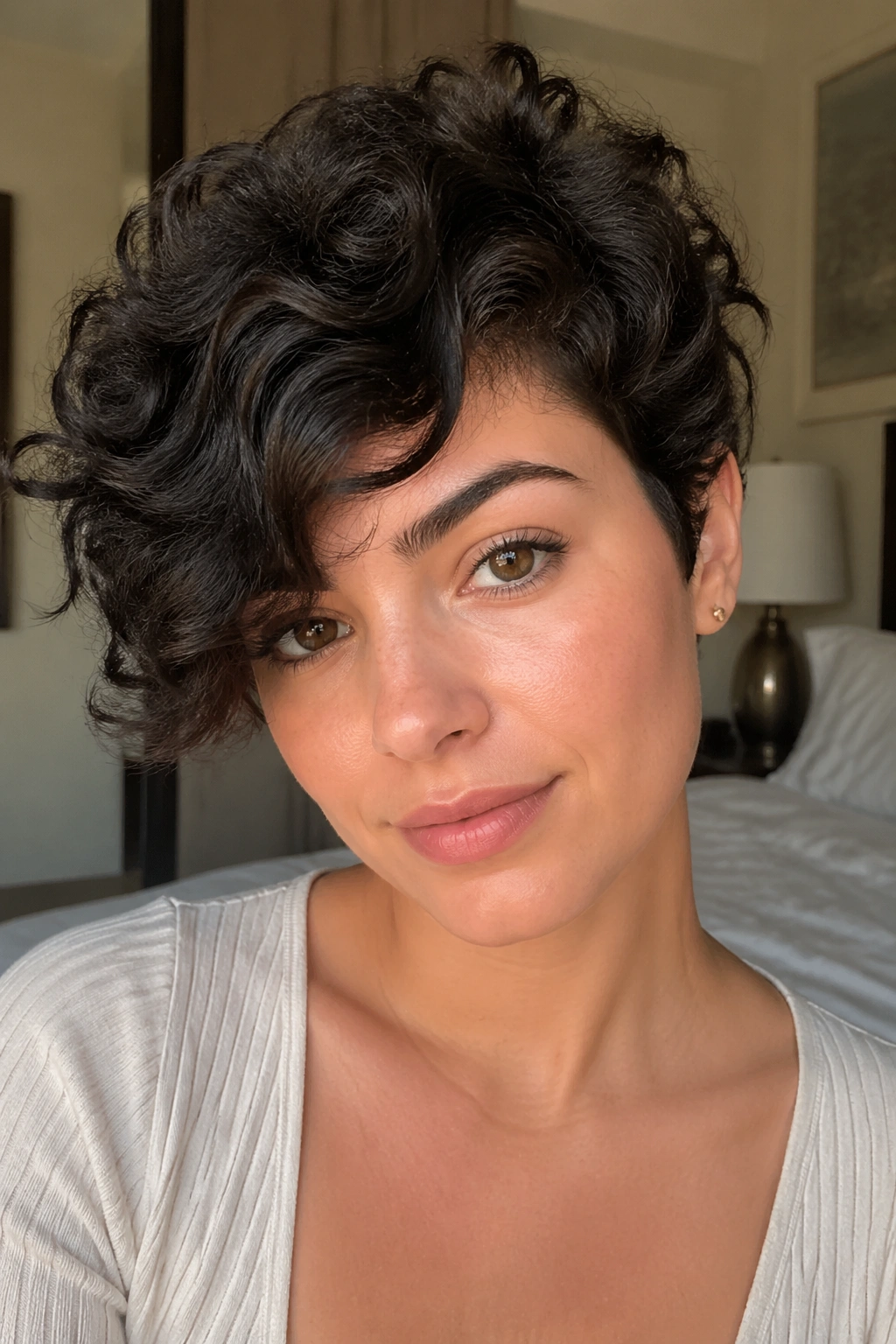 Close-up of a real woman with a curly pixie and side sweep hairstyle in warm window light