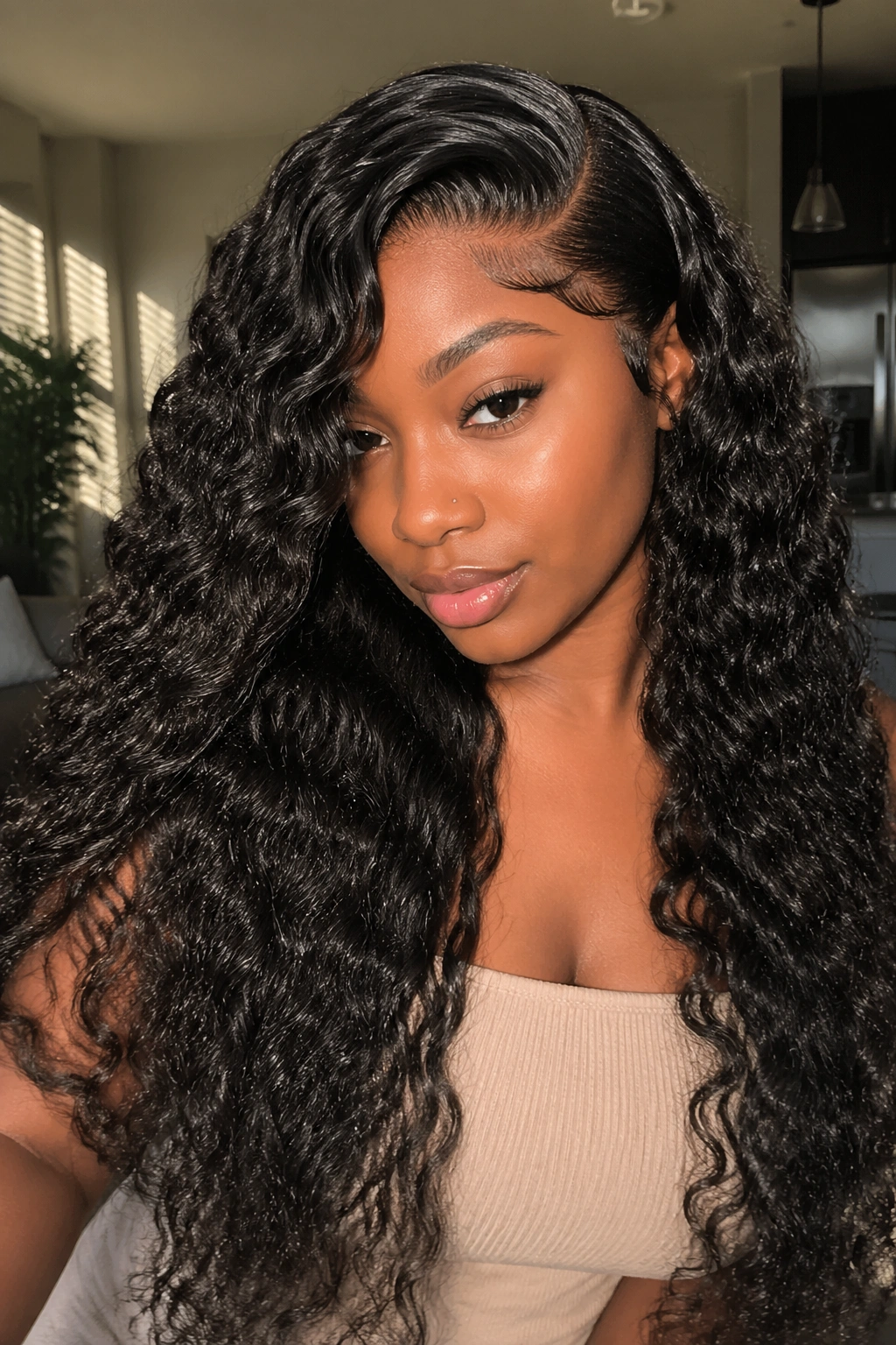 Close-up portrait of a real Black woman with deep side-part curly weave and waist-length layers in a sunlit living room