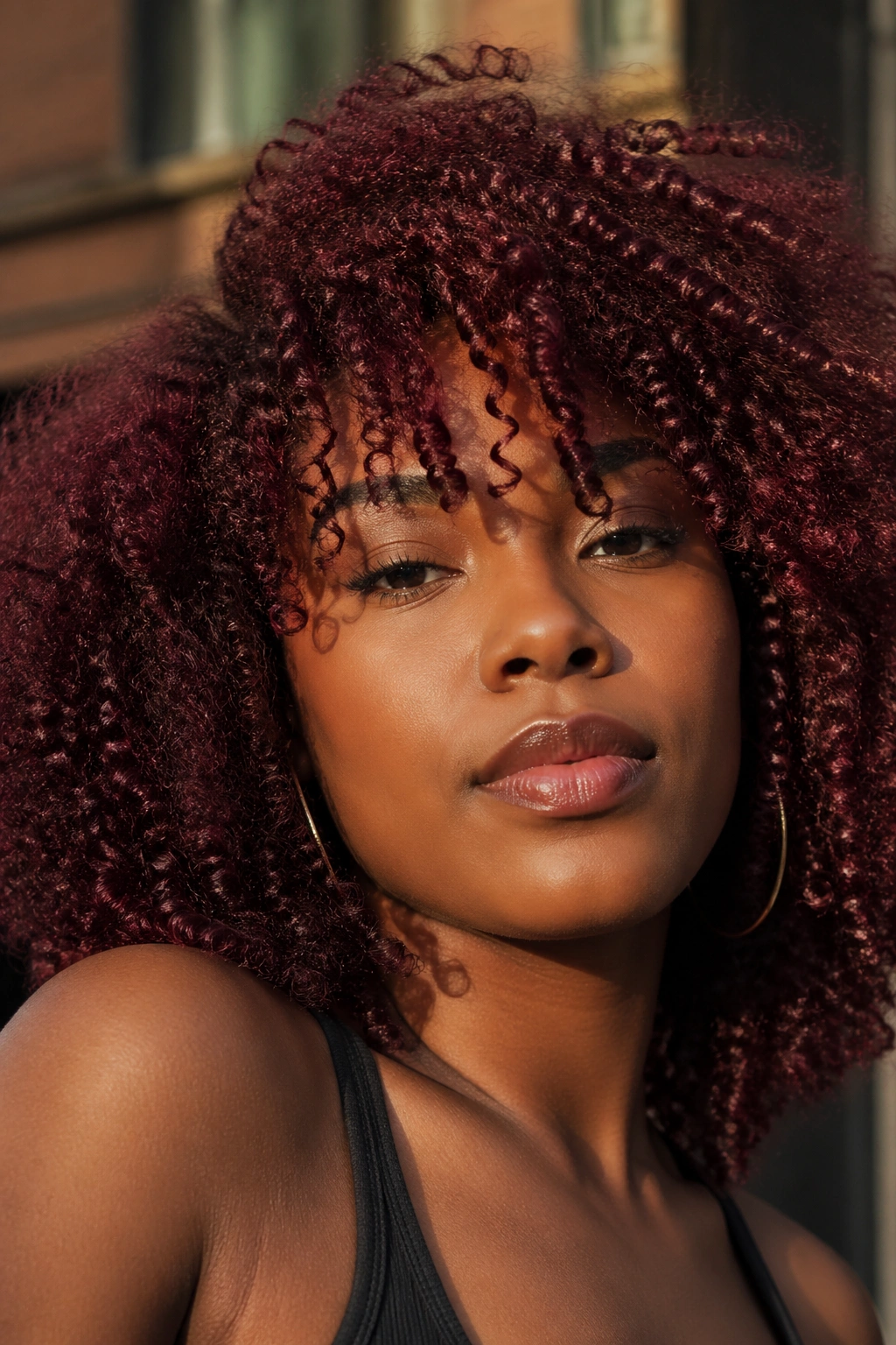 Close-up portrait of a real woman with dark cherry red curls.