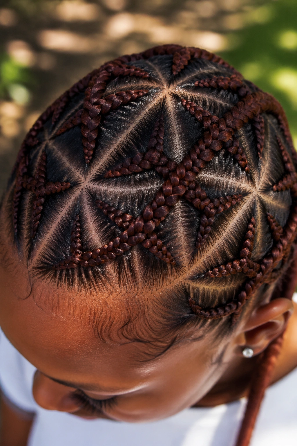 Close-up of geometric diamond cornrow pattern on auburn hair of a real person.