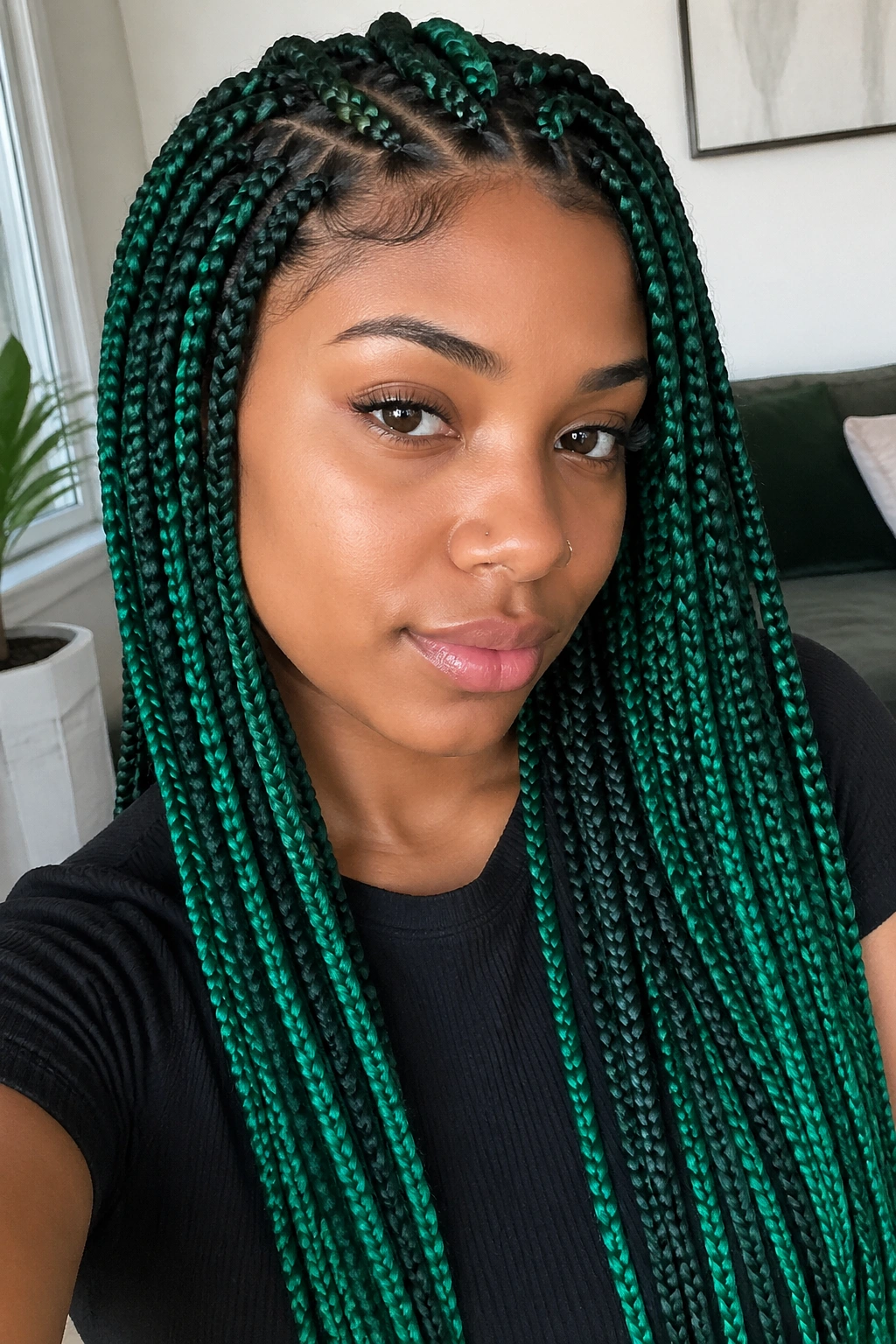 Real person with emerald and forest green box braids in soft natural light.