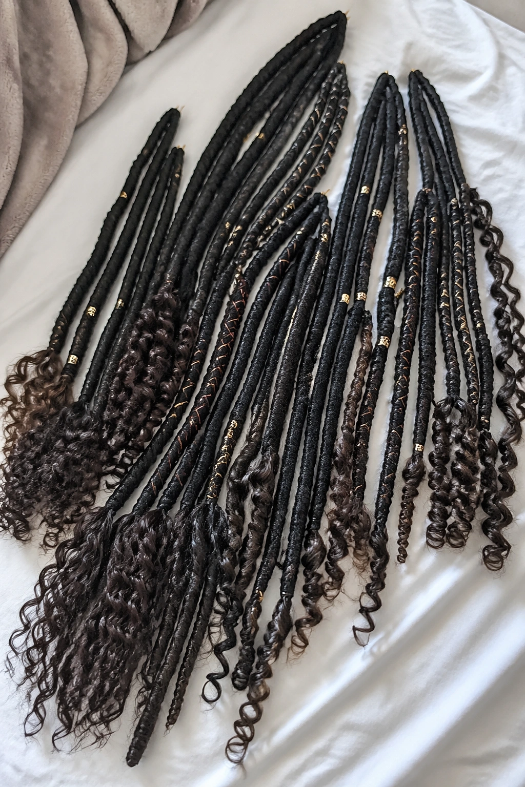 Overhead flat-lay of faux loc-inspired twists with curly ends and wraps.
