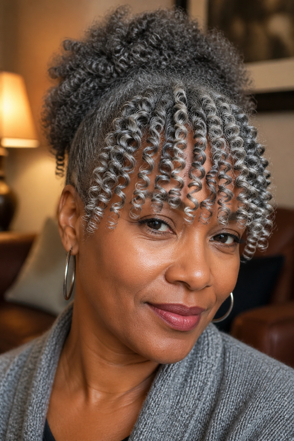 Close-up of a woman with finger-coiled grey bangs and a puff behind.