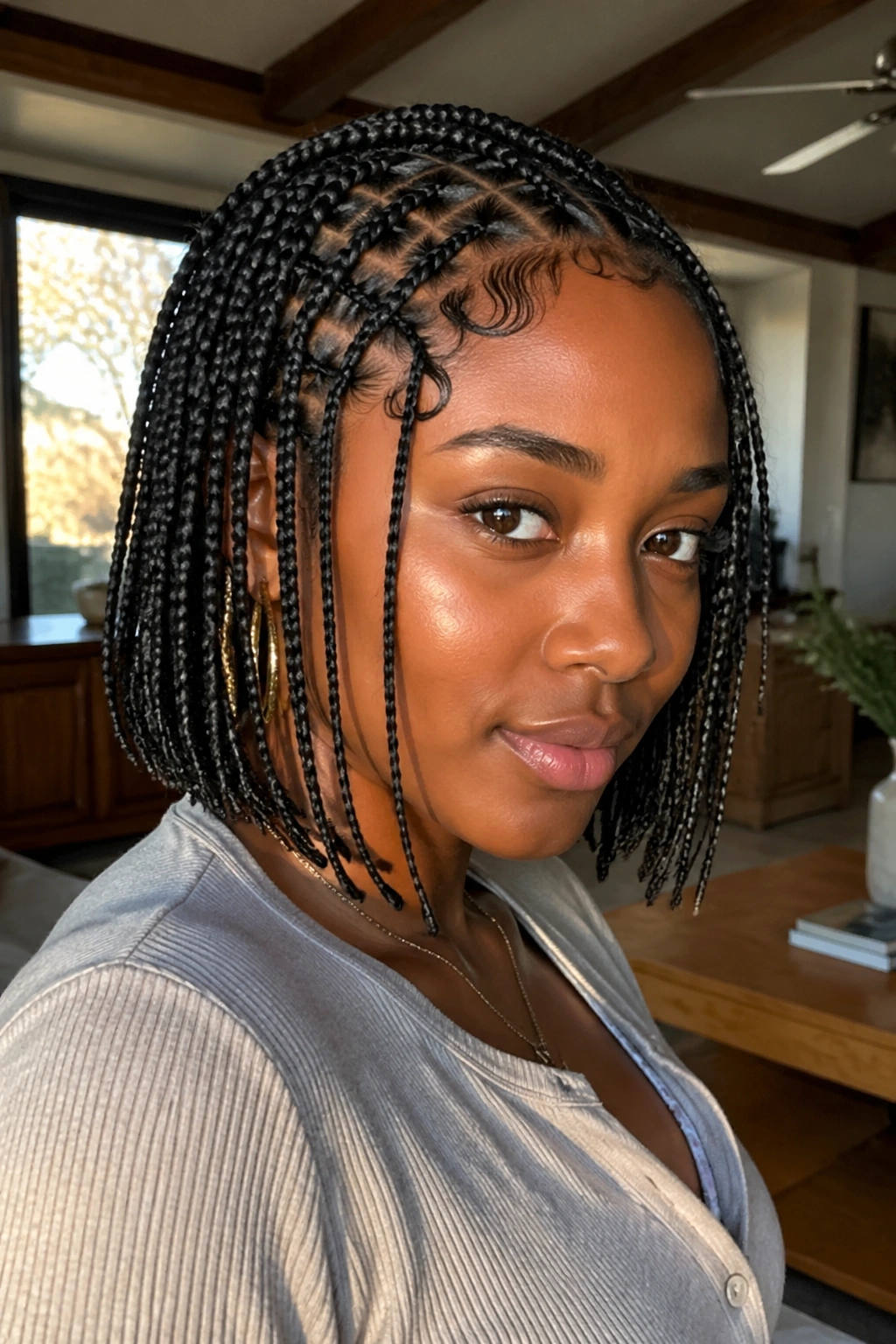 Close-up portrait of a real woman with Fulani-inspired bob featuring crown cornrows and chin-length hanging braids.