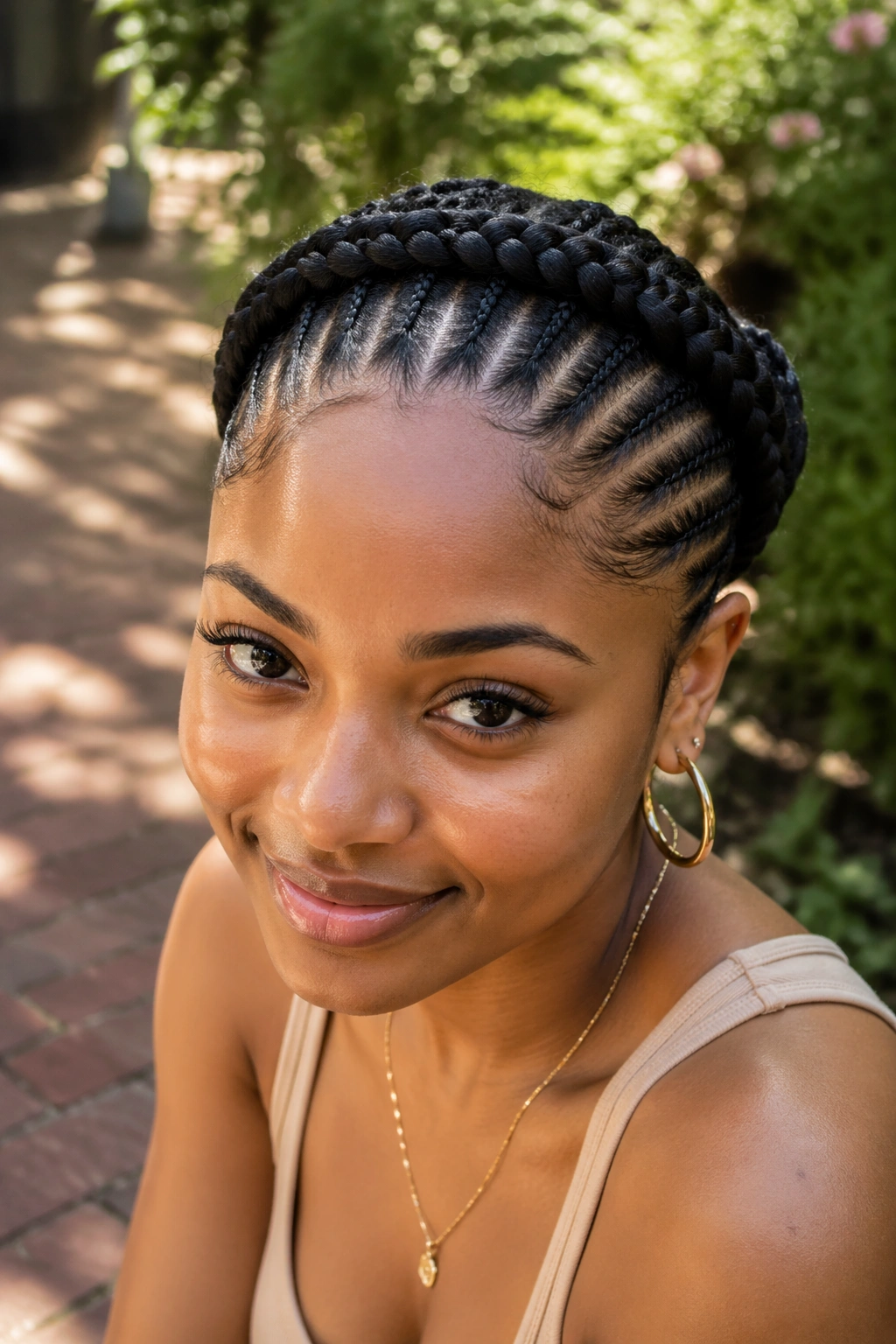 Close-up of a real woman with a halo of cornrows around her head in natural garden light