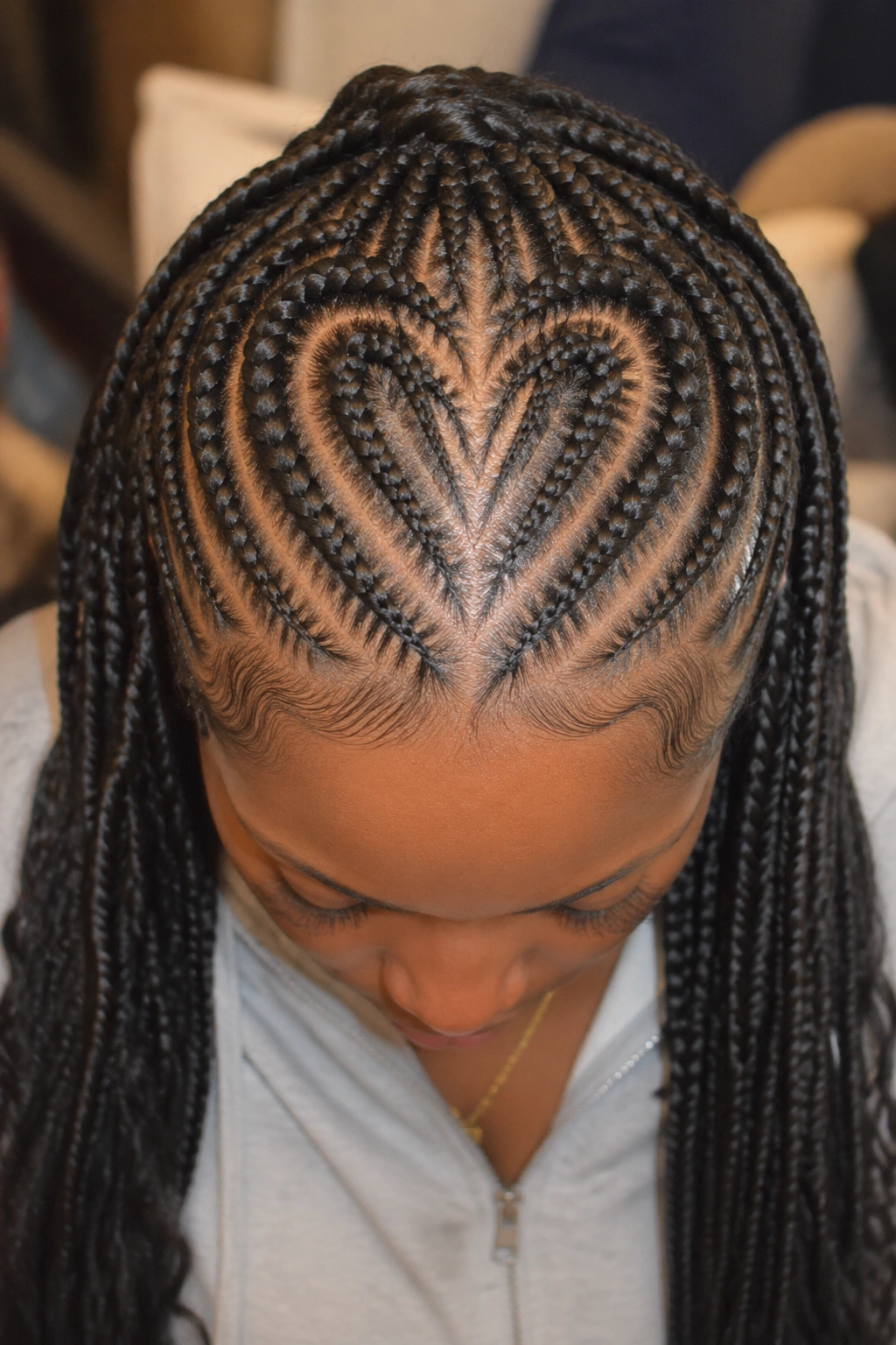 Top-down view of a real woman with heart-shaped stitched cornrows transitioning to box braids