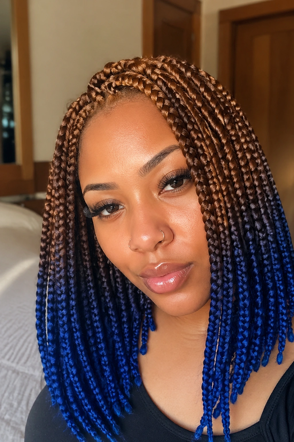 Close-up portrait of a real woman with honey brown roots and cobalt blue ends in box braids.