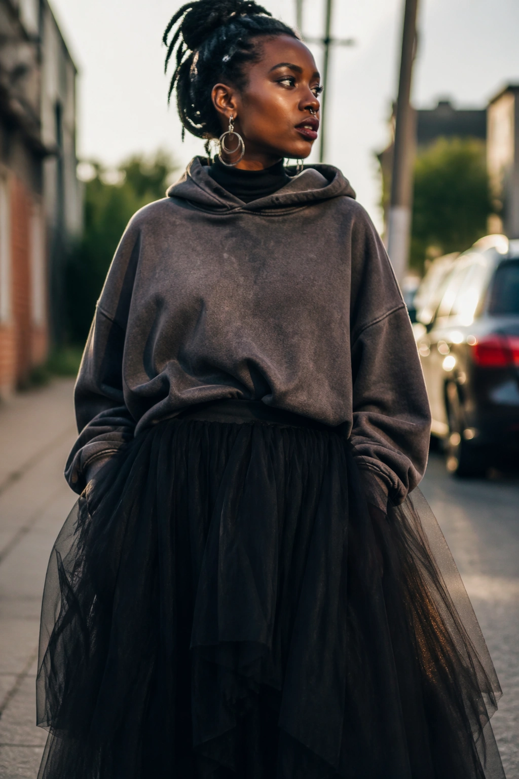 Model in oversized hoodie and dramatic tulle skirt on city street.