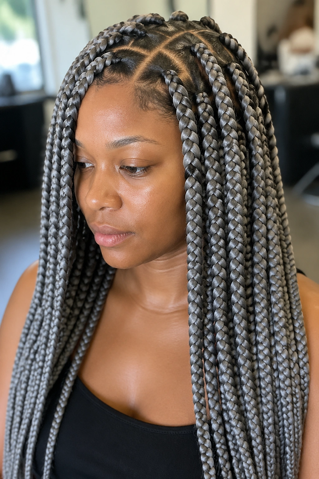 Close-up portrait with jumbo grey box braids and crisp parts on a real woman in a bright salon