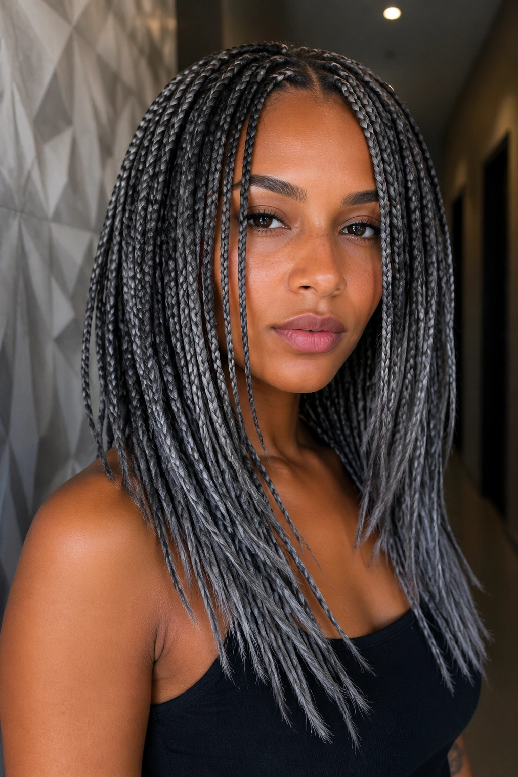 Close-up of a woman with layered grey box braids with uneven ends.
