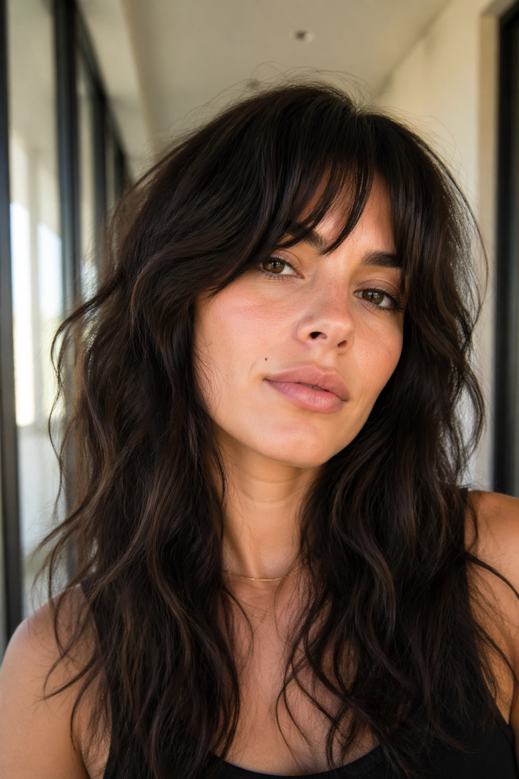 Close-up of a woman with long wavy shag and bottleneck bangs