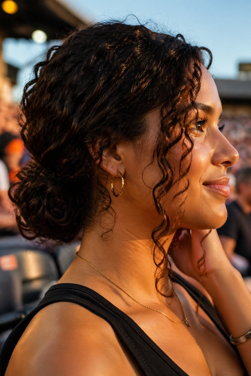 Close-up of a real person with a low curly bun and face-framing pieces