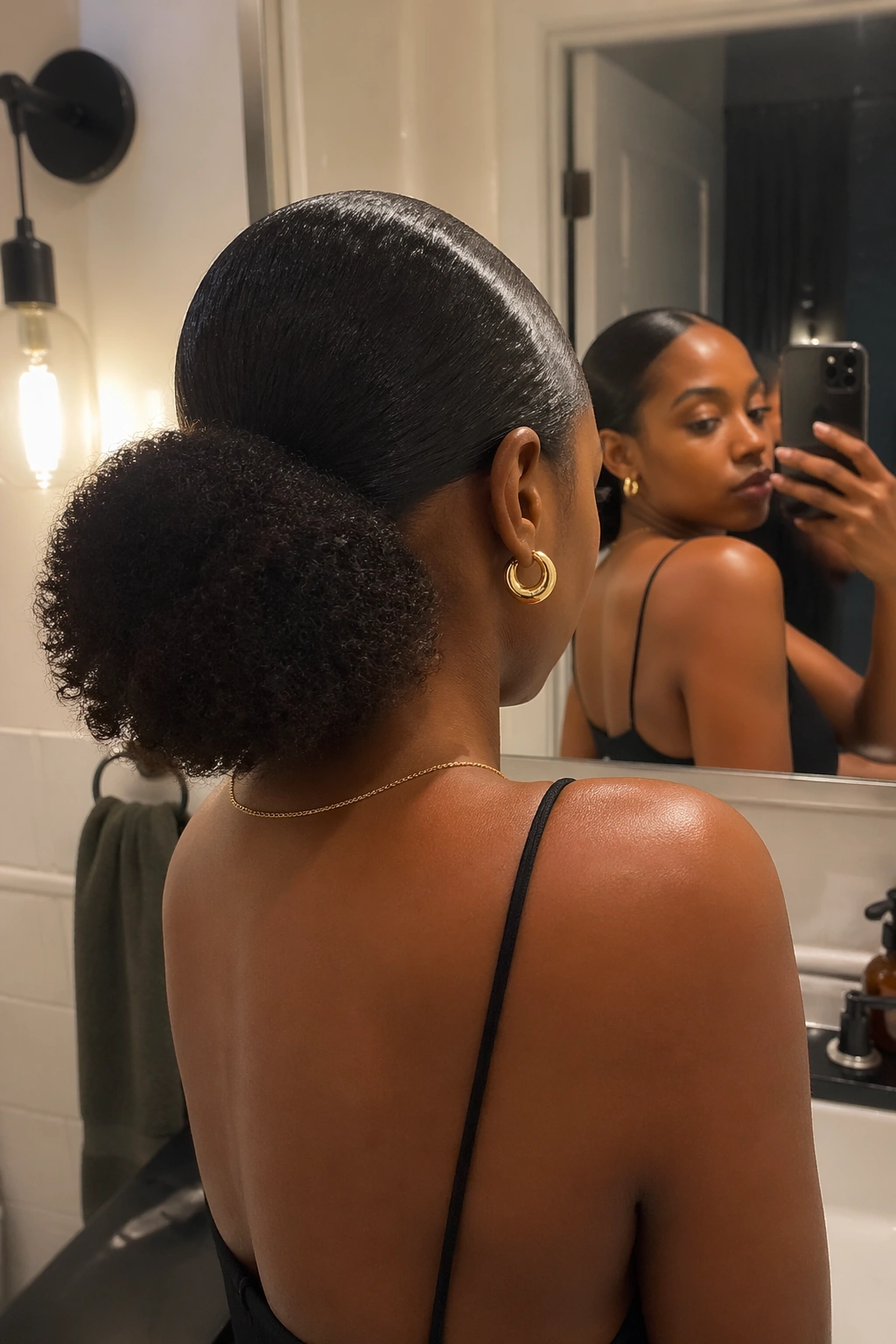 Over-the-shoulder shot of a low puff ponytail in a bathroom mirror.