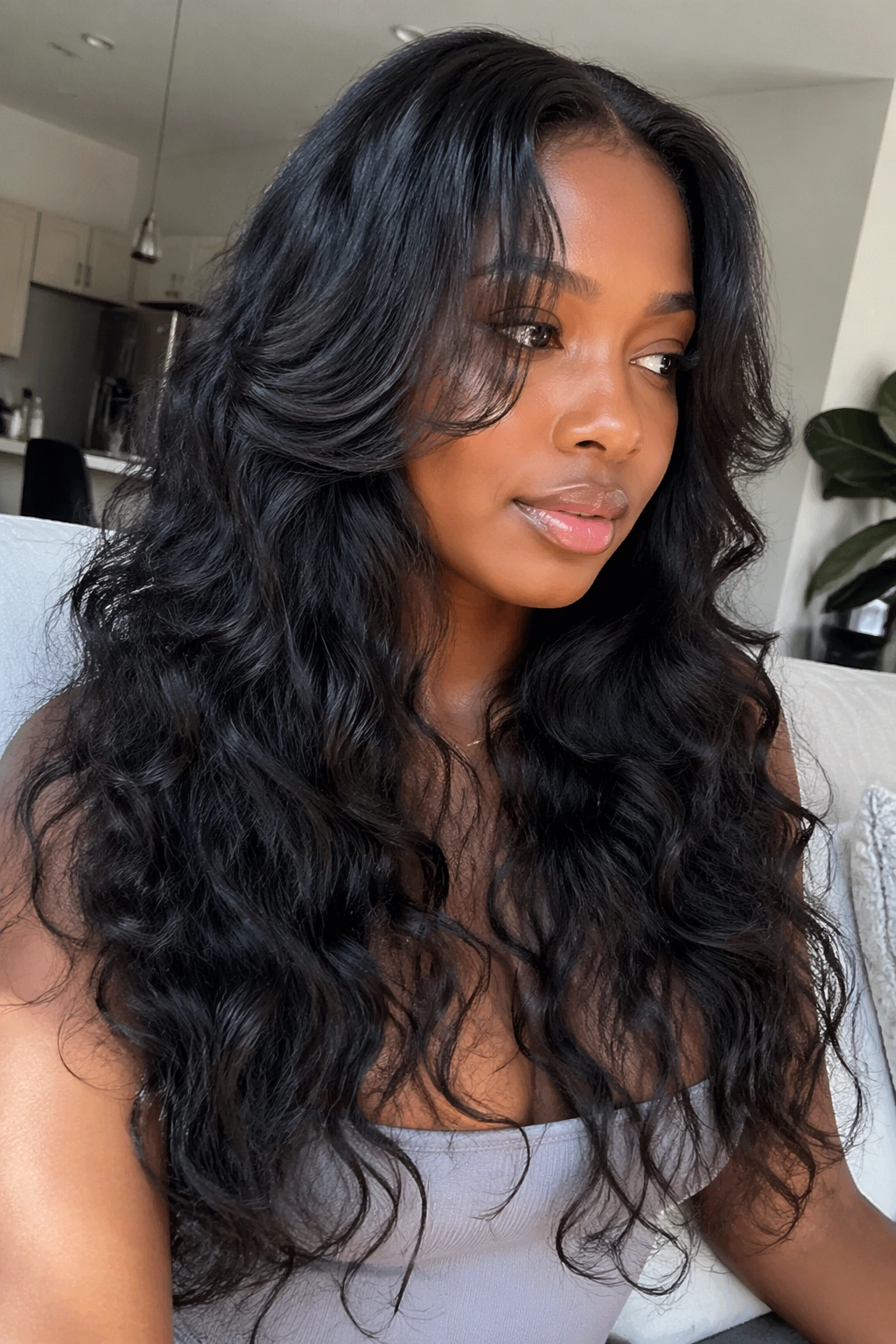 Real woman with long layered mermaid curls framing the face in a bright room