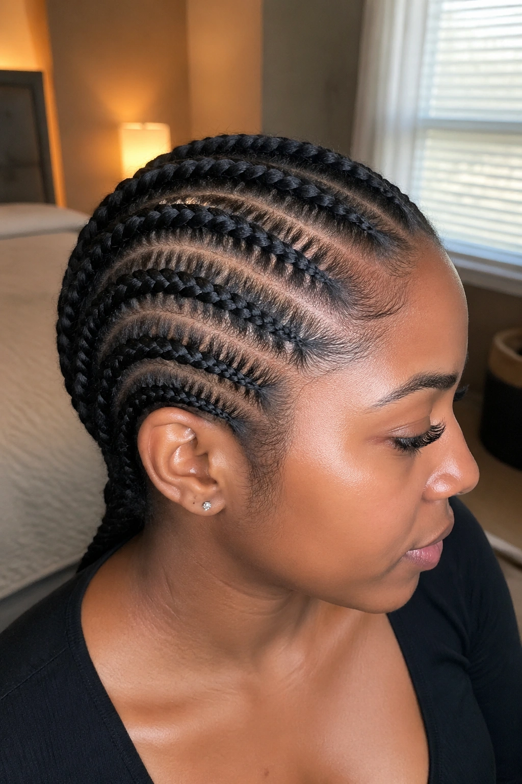 Close-up of real woman with five to six narrow Marley cornrows across the scalp under natural window light