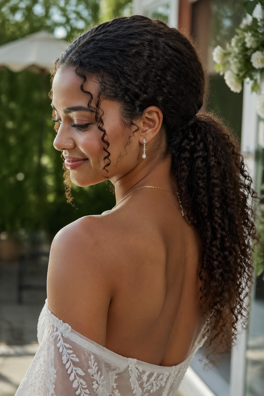Bride with natural curls gathered into a low ponytail
