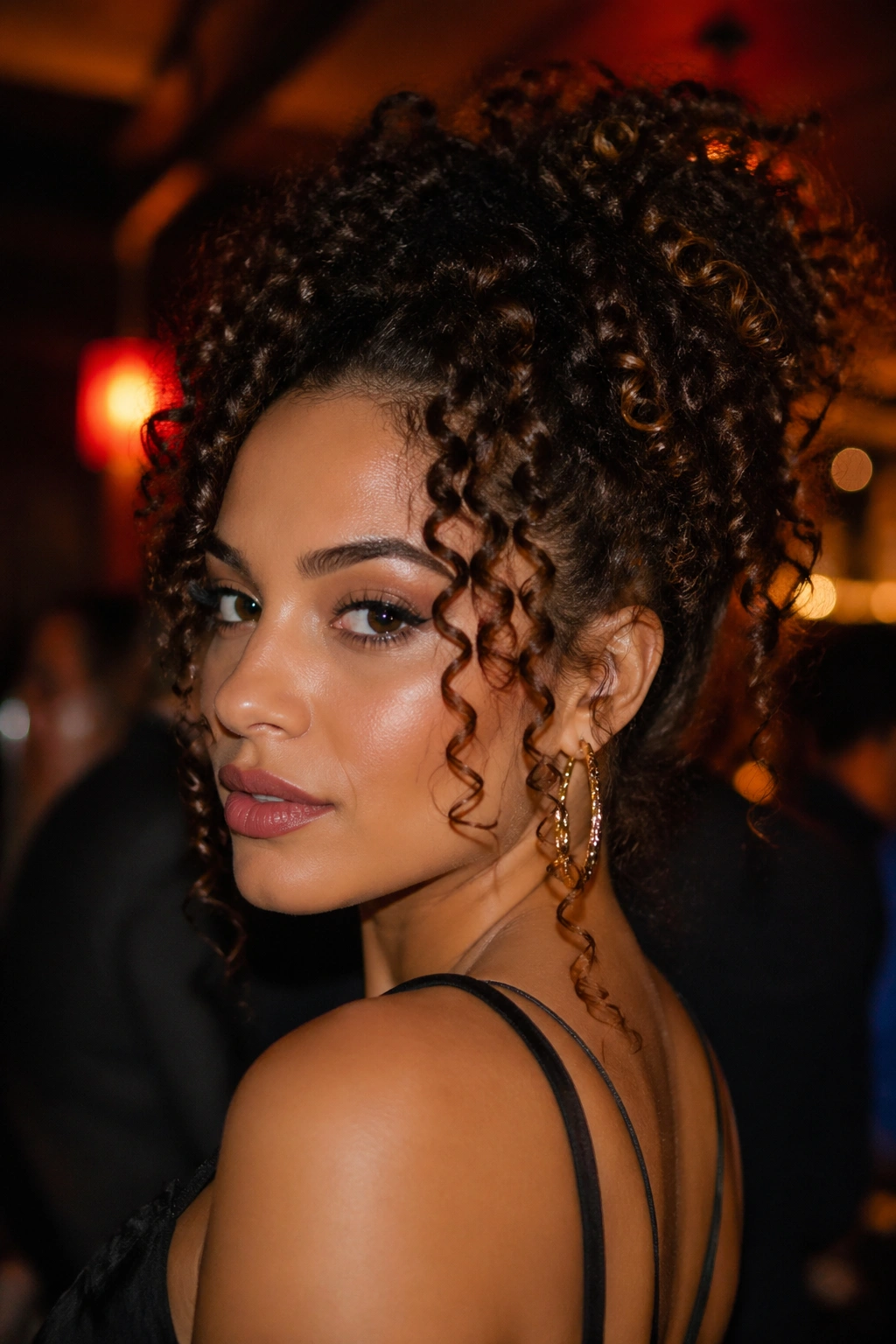 Close-up portrait of a woman with bold, defined curls under warm nightclub lighting