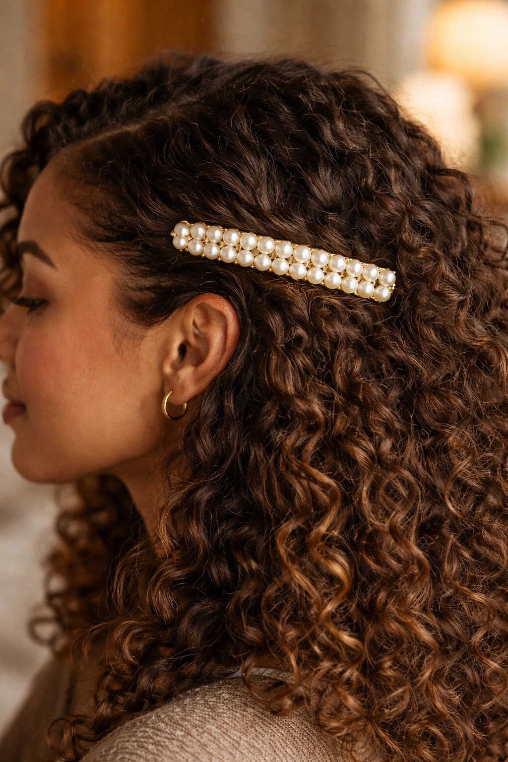 Long pearl barrette securing side-swept curls on a real person.