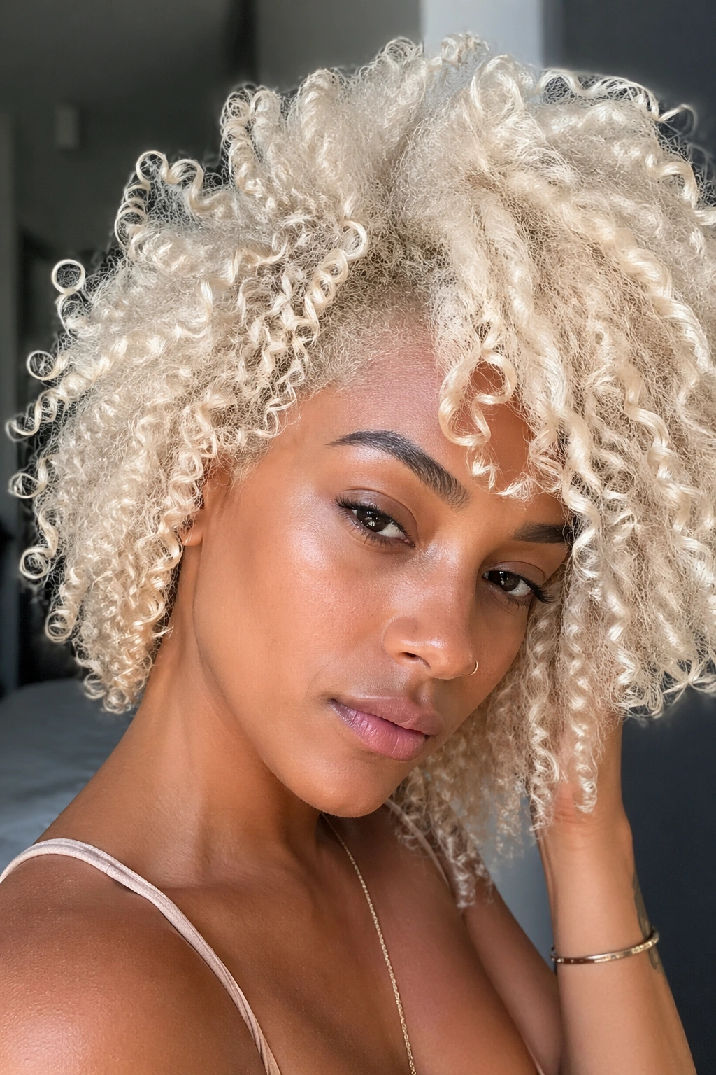 Close-up of a real person with full platinum blonde curls in soft light