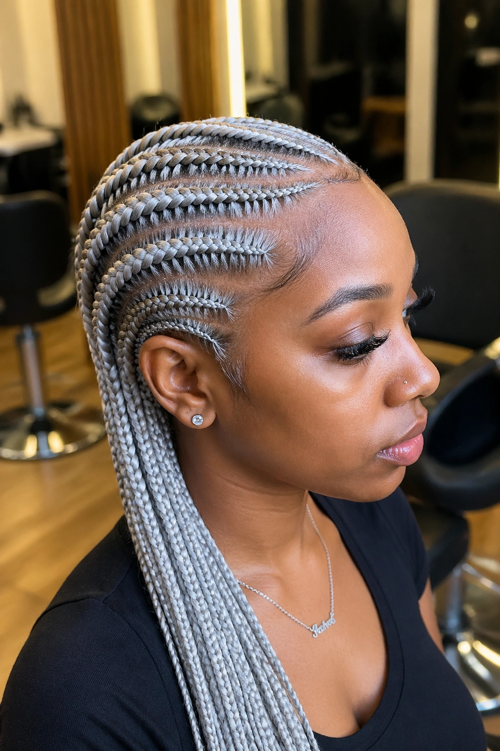 Close-up portrait of a real person with platinum silver feed-in cornrows in a warm salon setting