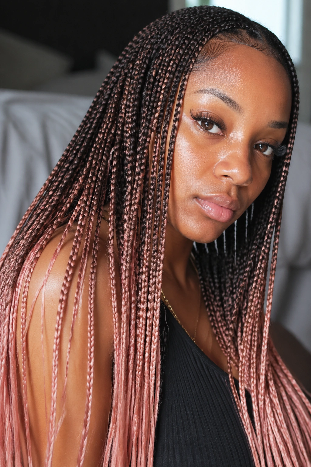 Close-up of real woman with micro braids ending in rose-gold tips under natural window light