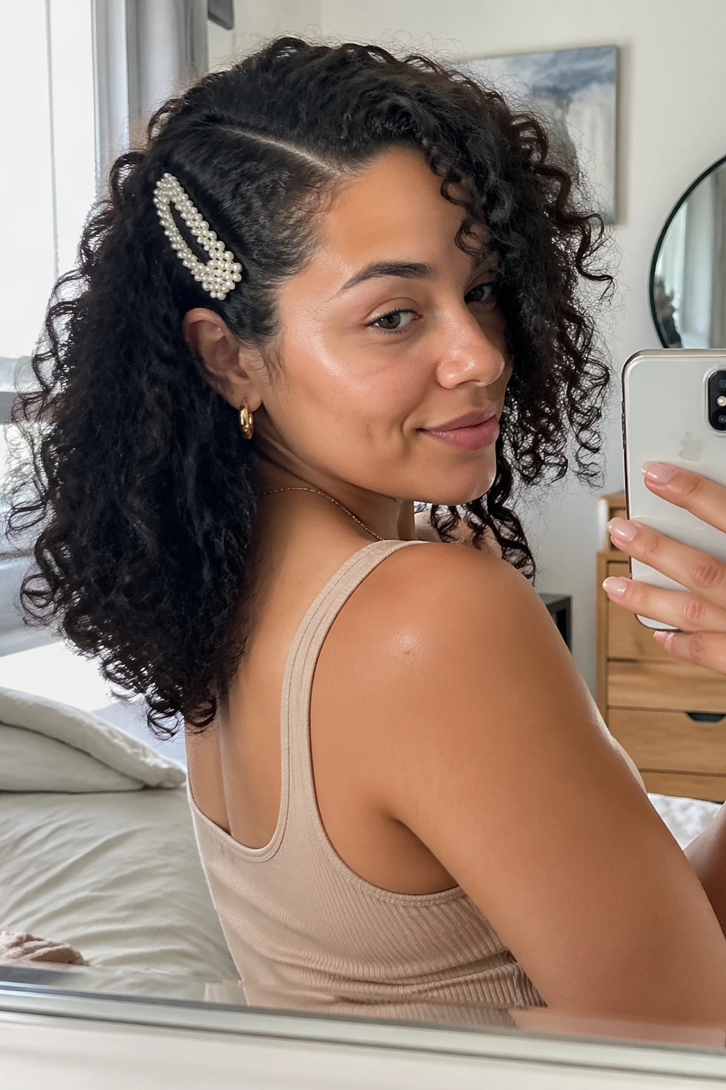 Over-the-shoulder mirror selfie of a deep side part with a barrette.