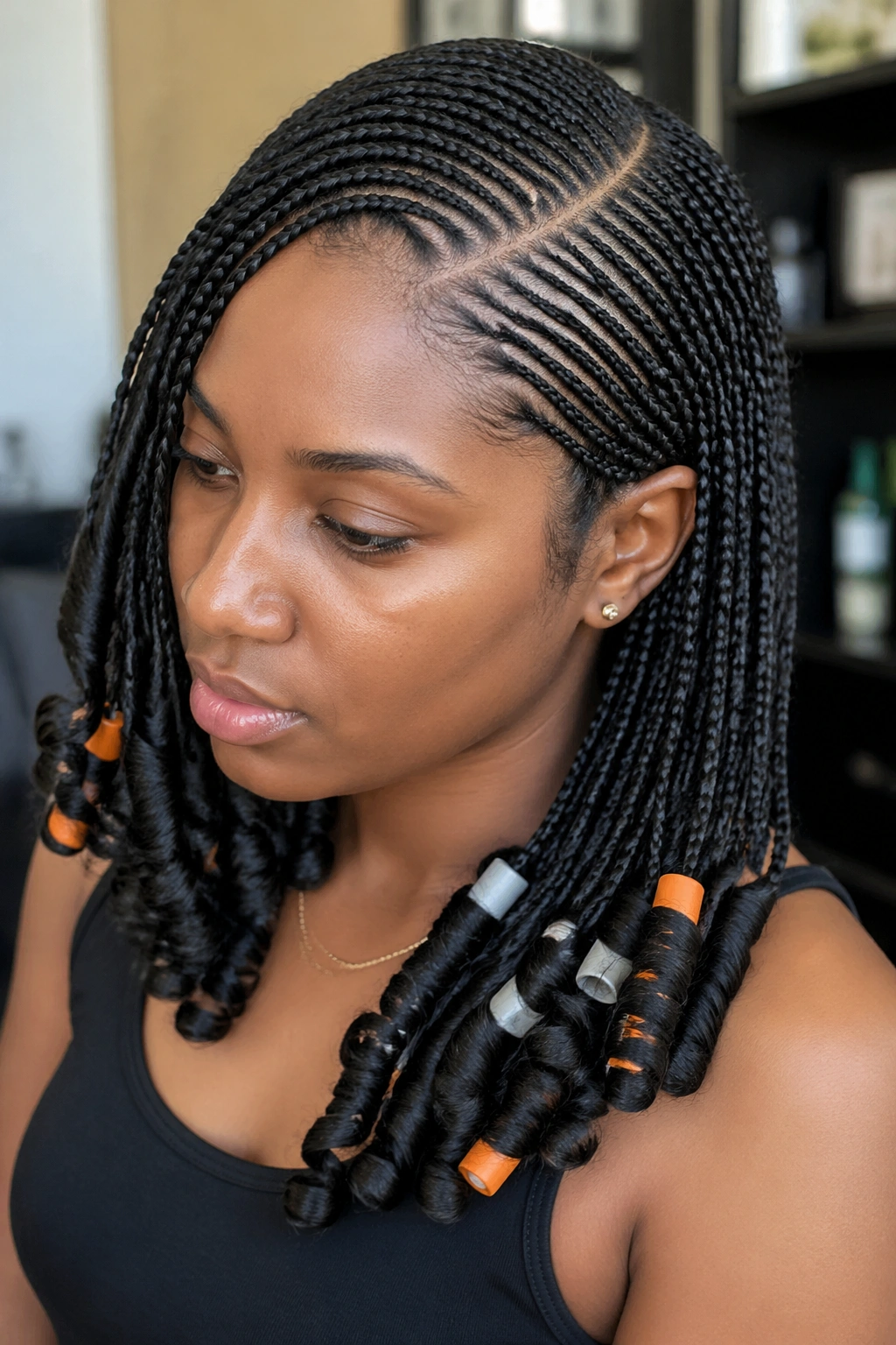 Close-up of side-swept cornrows with curled ends on a real person.