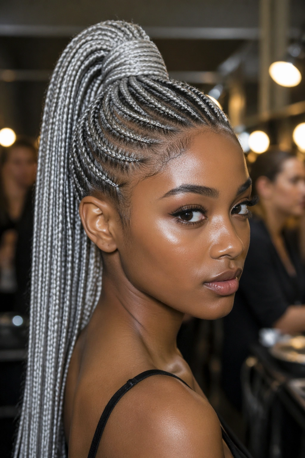 Close-up of silver cornrows forming a high crown ponytail on a real person.