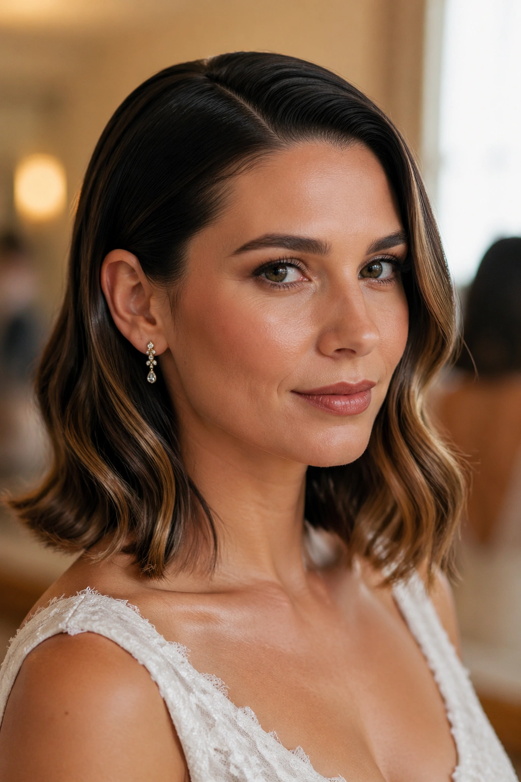 Close-up of a woman with sleek roots and wavy ends in a bridal suite setting