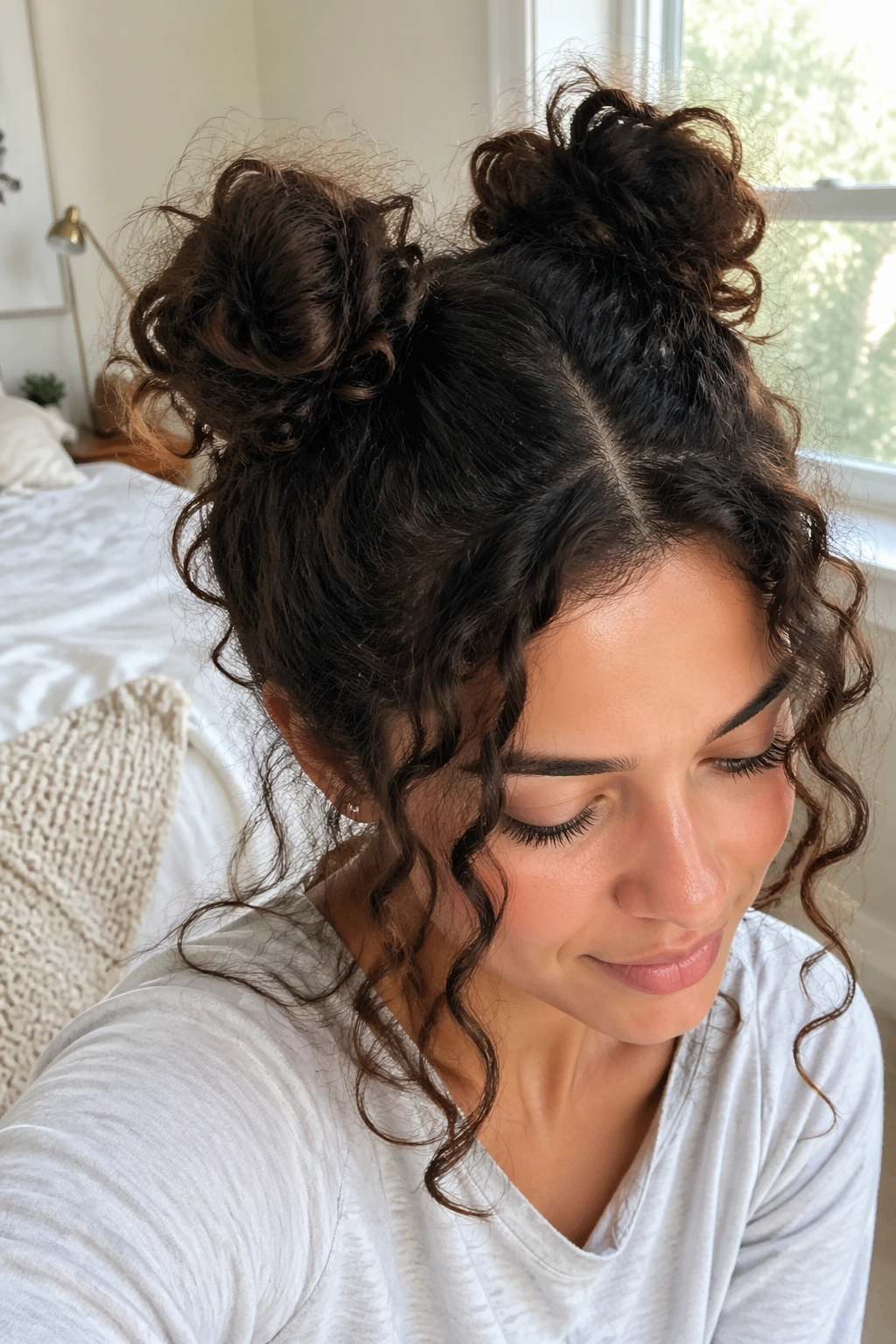 Close-up of a woman with two small high space buns and voluminous curls
