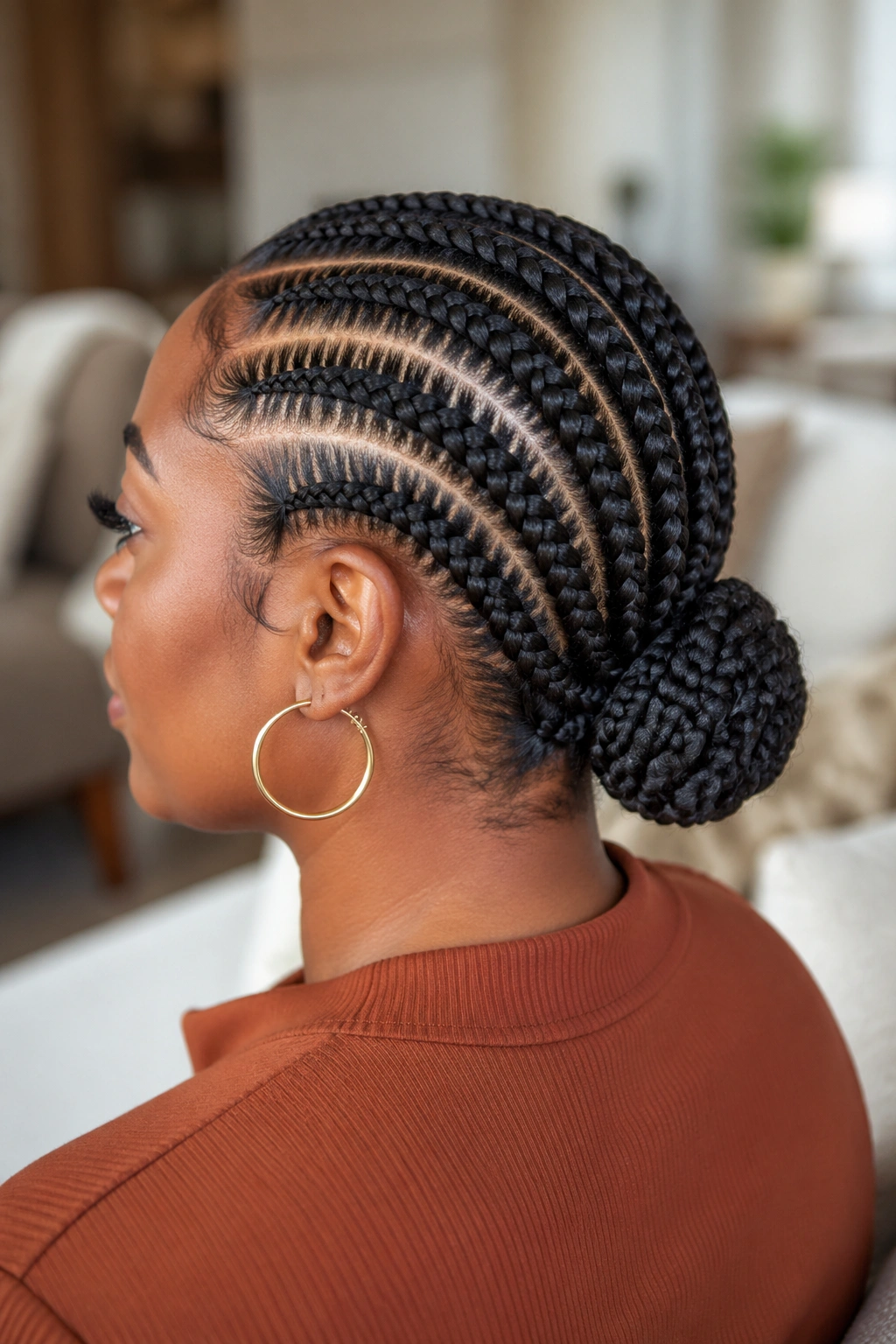 Side/back close-up of a real woman with stitch cornrows forming a low bun